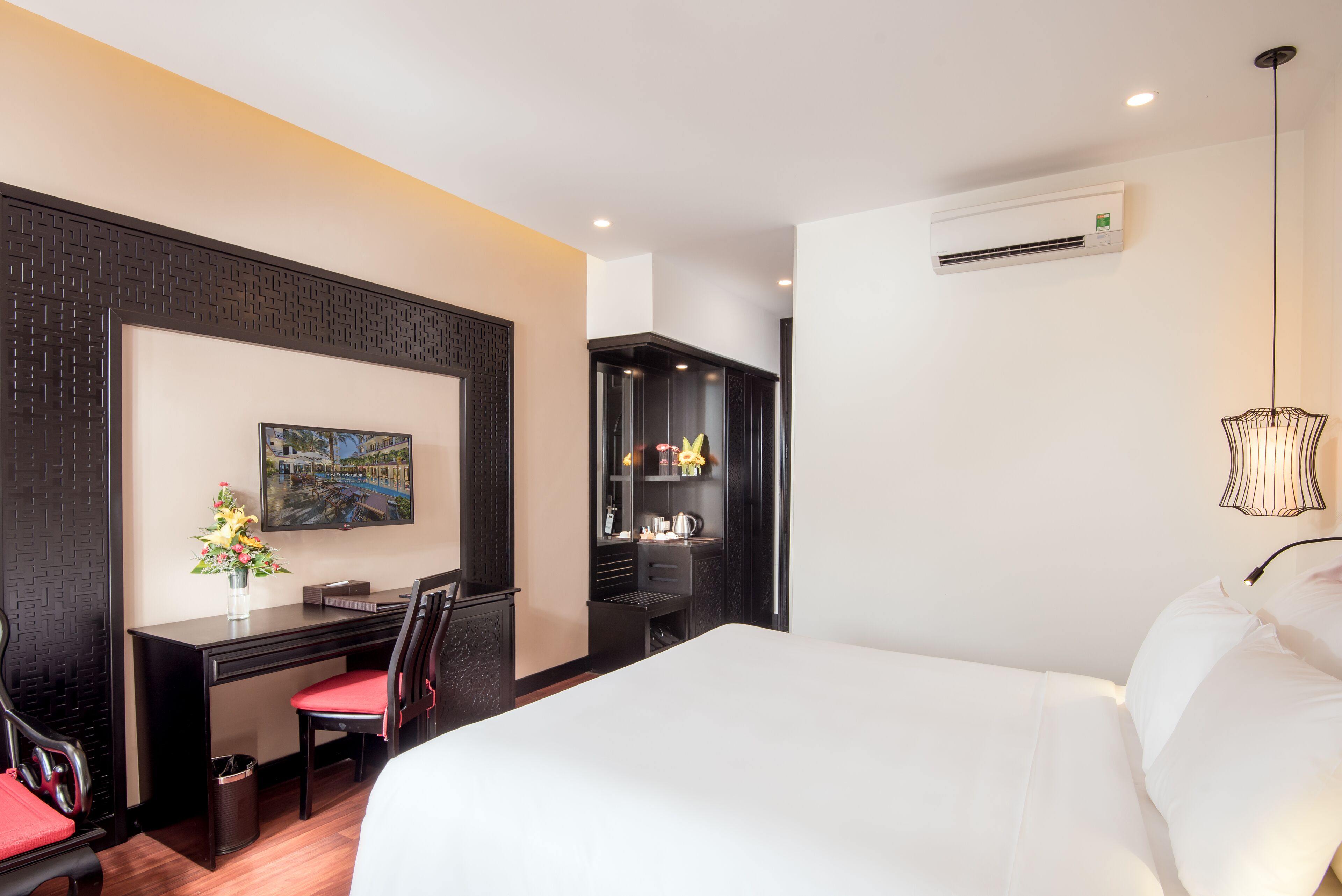 Una habitación de hotel con cama, escritorio, silla y una pequeña kitchenette.