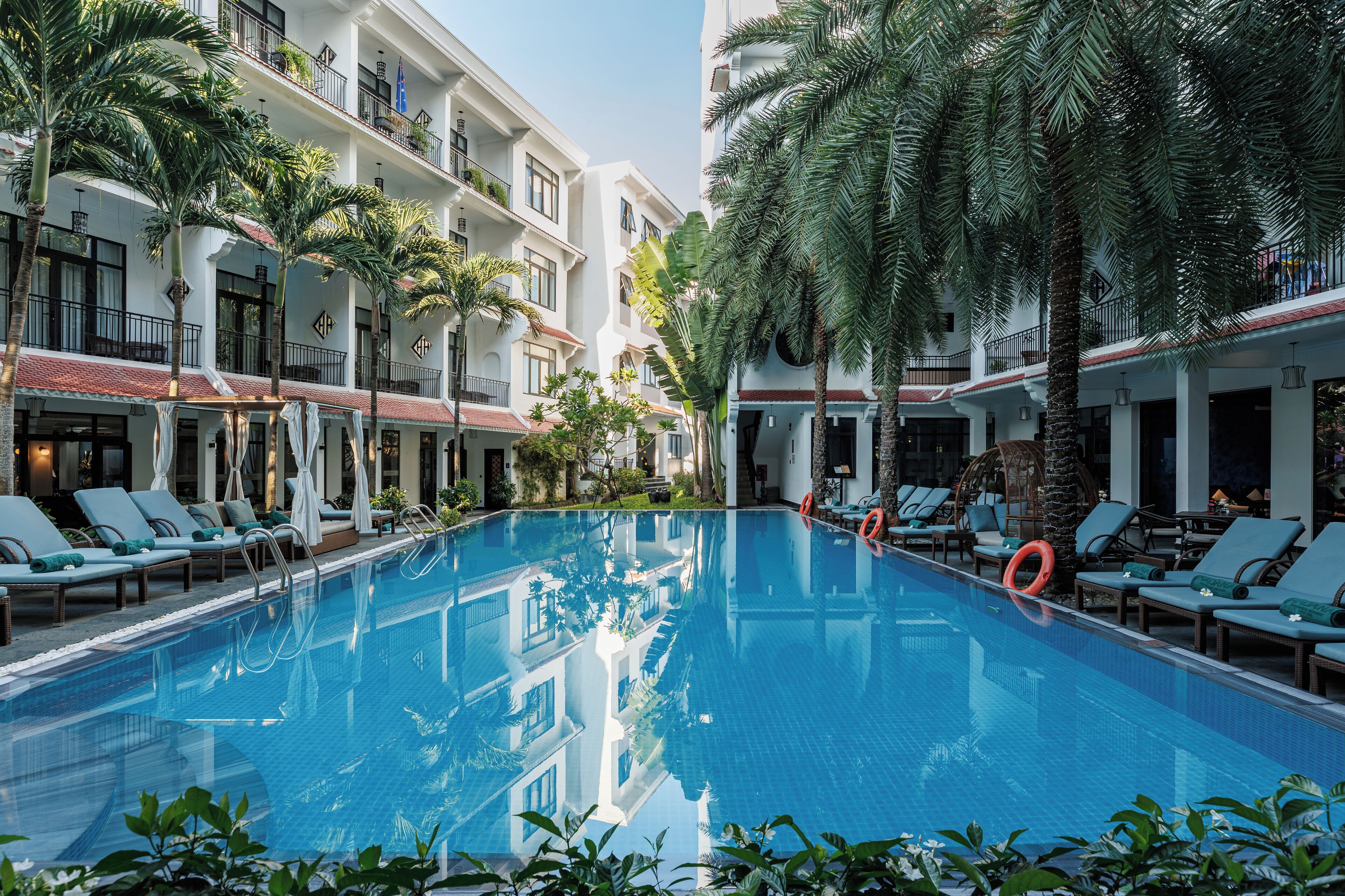 A swimming pool with lounge chairs and palm trees.