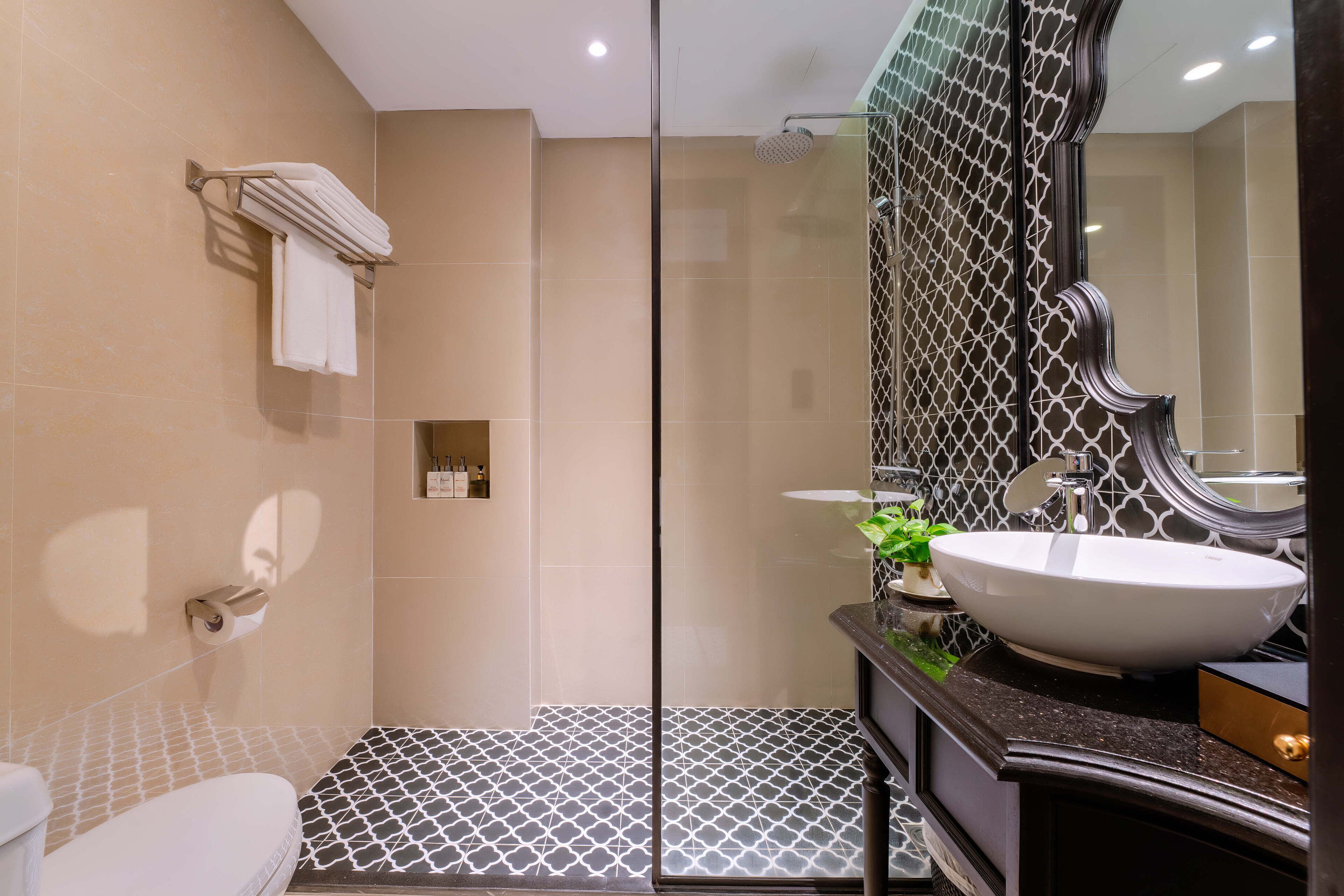 Ein modernes Badezimmer mit einer Glaskabine zur Dusche, einem großen Spiegel und einem weißen Waschbecken.