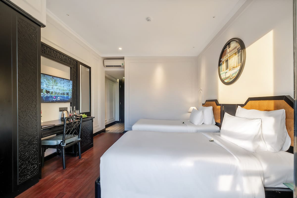A hotel room with a large bed, a desk with a chair, a TV, and a view of the outside.