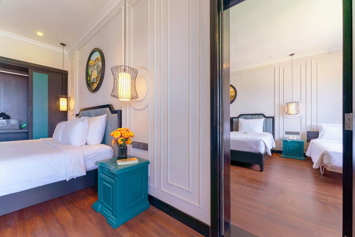 A hotel room with two beds, a teal nightstand, a mirror, and a painting on the wall.