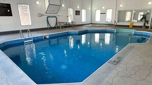 Une piscine intérieure à l’eau claire, entourée de murs carrelés et dotée d’un sol à motifs hexagonaux.