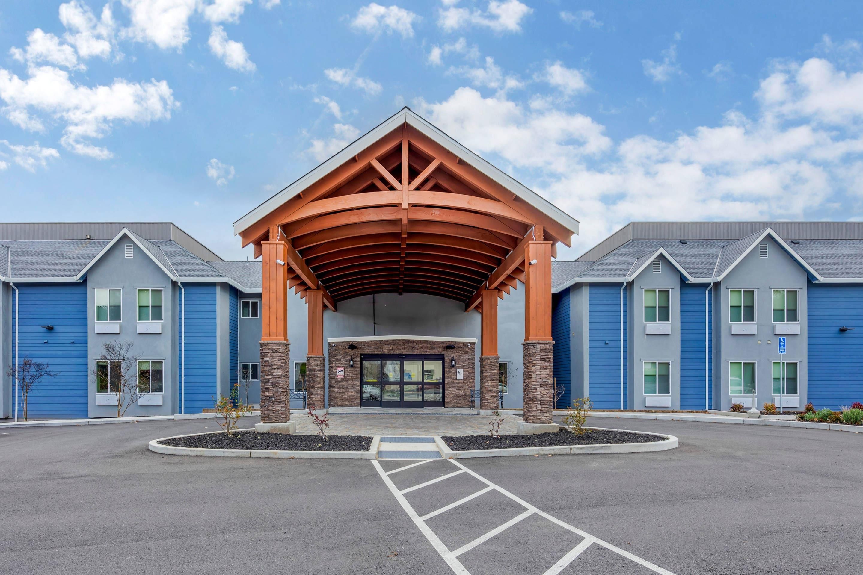 A building with a covered entrance, blue exterior walls, and a parking lot.