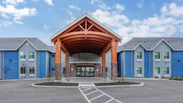 A building with a covered entrance, blue exterior walls, and a parking lot.