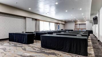 A conference room with multiple tables, a carpeted floor, and a ceiling with recessed lighting.