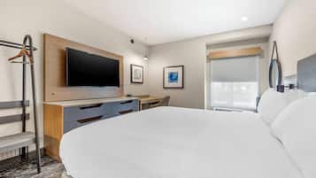 Una habitación de hotel moderna con una cama grande, un escritorio, un televisor de pantalla plana y una ventana con persianas.