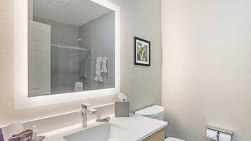 Un baño moderno con un espejo grande, un lavabo, un inodoro y un cuadro en la pared.