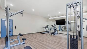 Ein Fitnessraum mit Trainingsgeräten, Laufband und Spiegel.