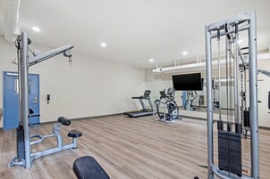 Un gimnasio con equipo de ejercicio, una cinta de correr y un espejo.