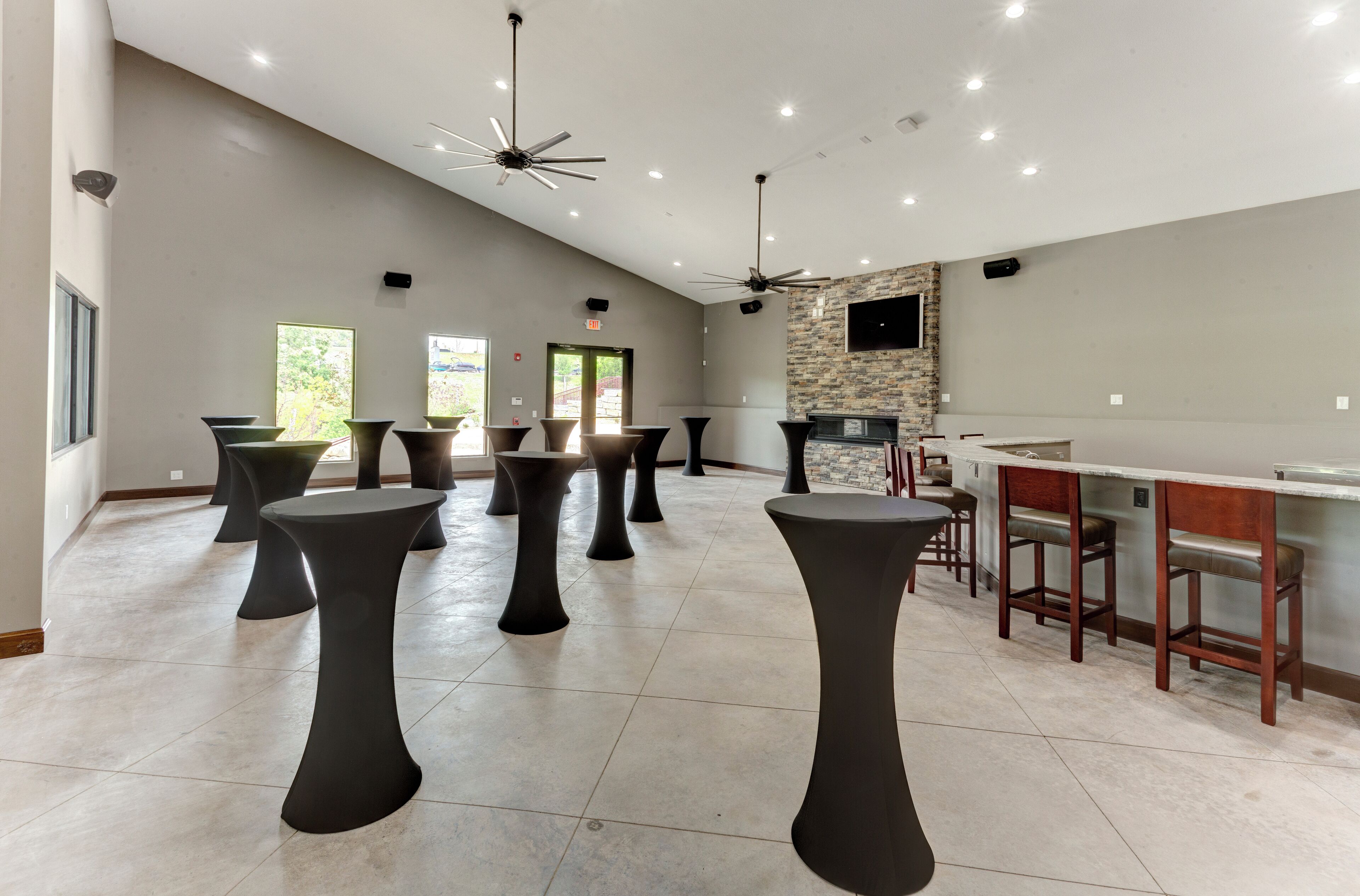 A spacious indoor area with multiple black stools and a bar area with wooden stools.