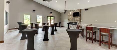 A spacious indoor area with multiple black stools and a bar area with wooden stools.