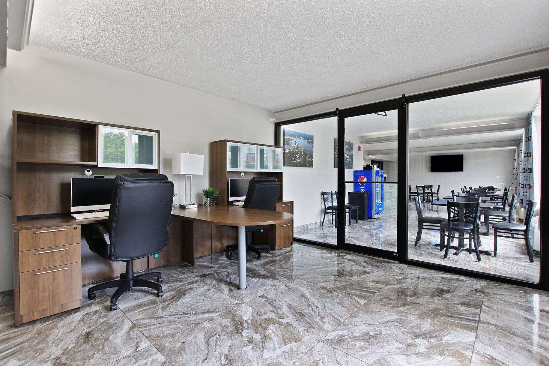 An office with a desk, chairs, and a large glass door leading to a dining area.