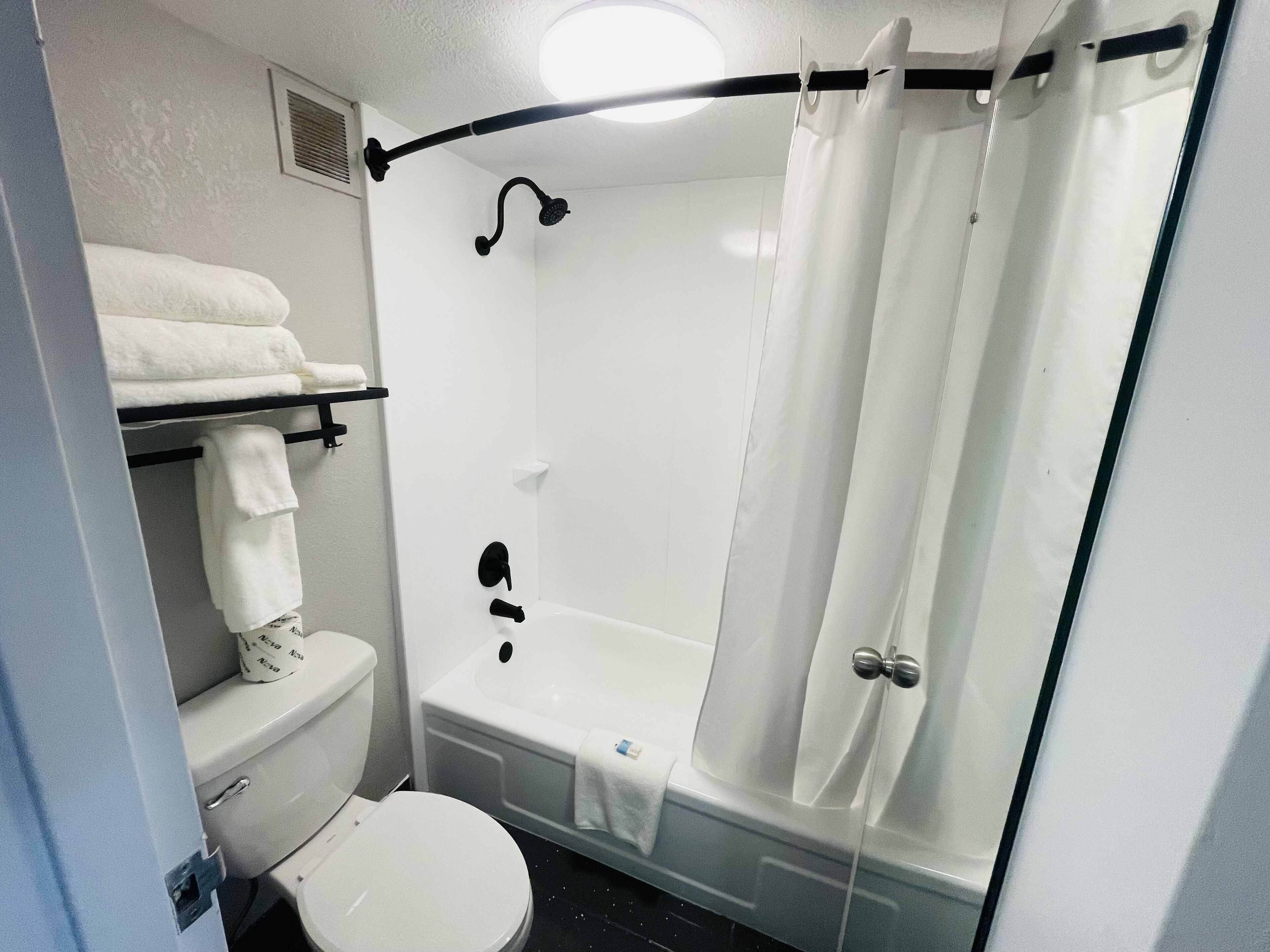 Un baño con inodoro, bañera y cortina de ducha.