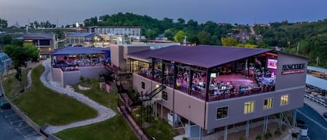 A multi-story building with a restaurant on the ground floor, outdoor seating, and a parking lot.