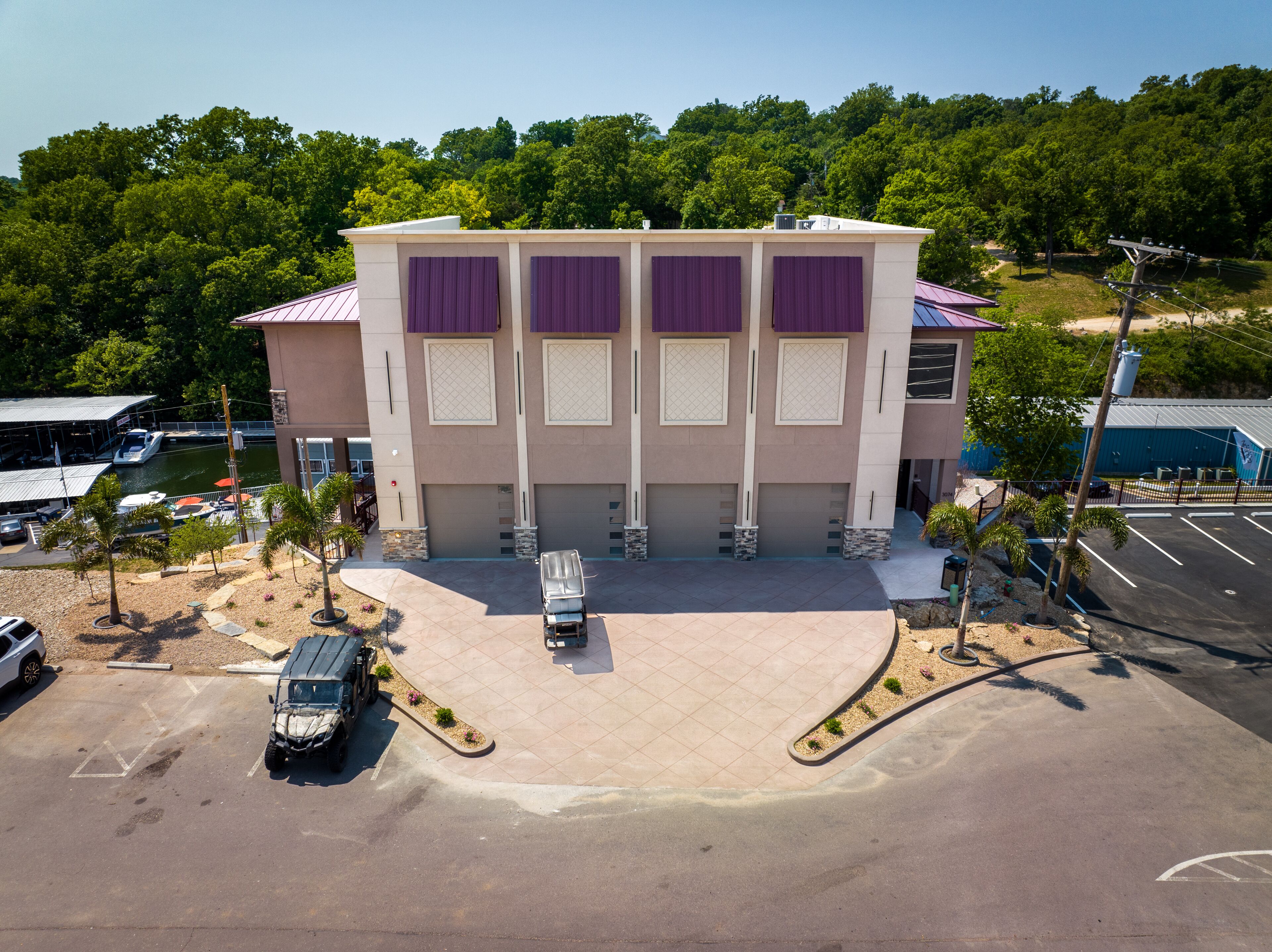 A multi-story building with a flat roof, large windows, and a parking lot with a few vehicles.