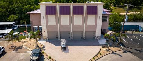 A multi-story building with a flat roof, large windows, and a parking lot with a few vehicles.