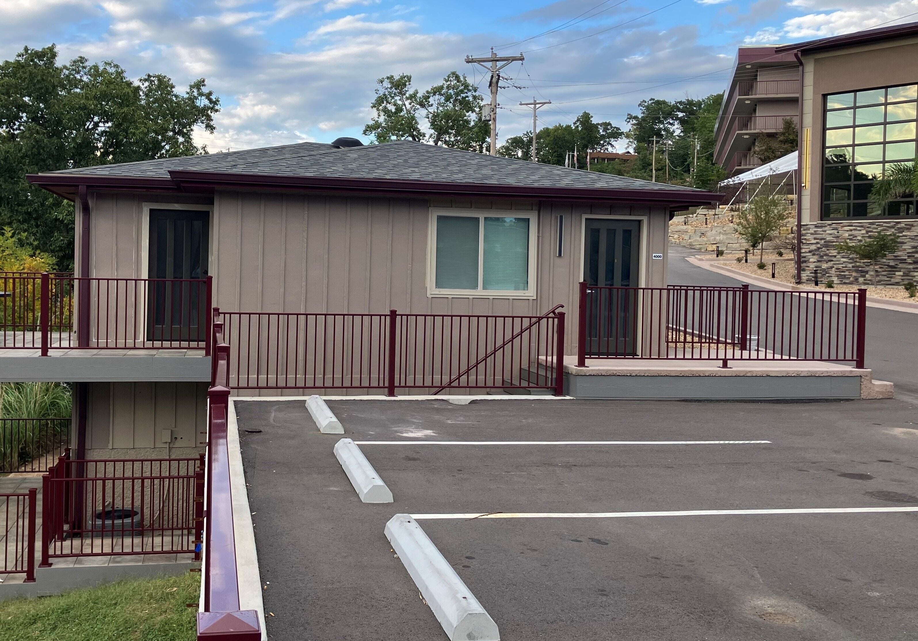 A small, single-story building with a red metal fence, a garage door, and a clear sky in the background.