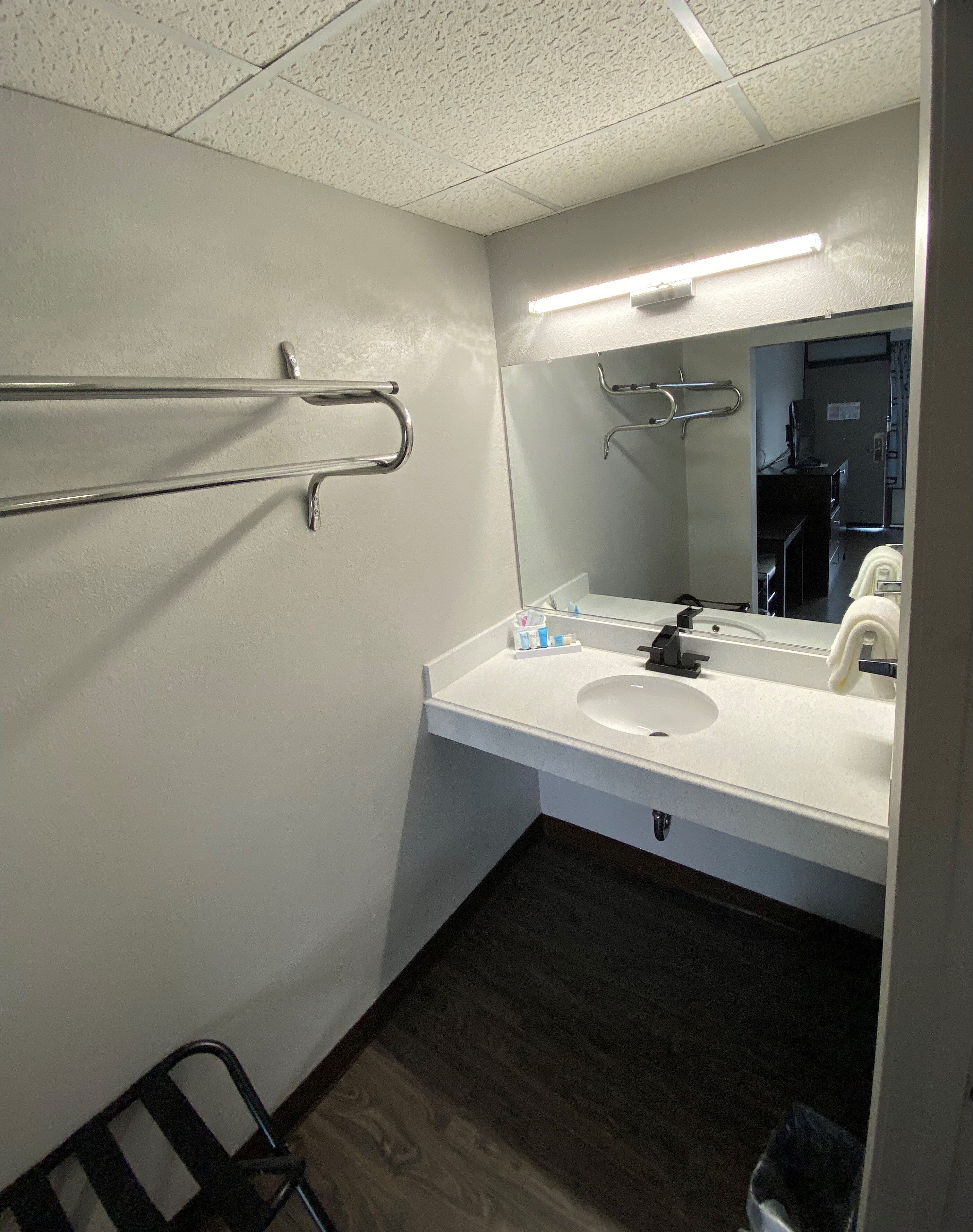 A bathroom with a white sink, mirror, and towel rack.