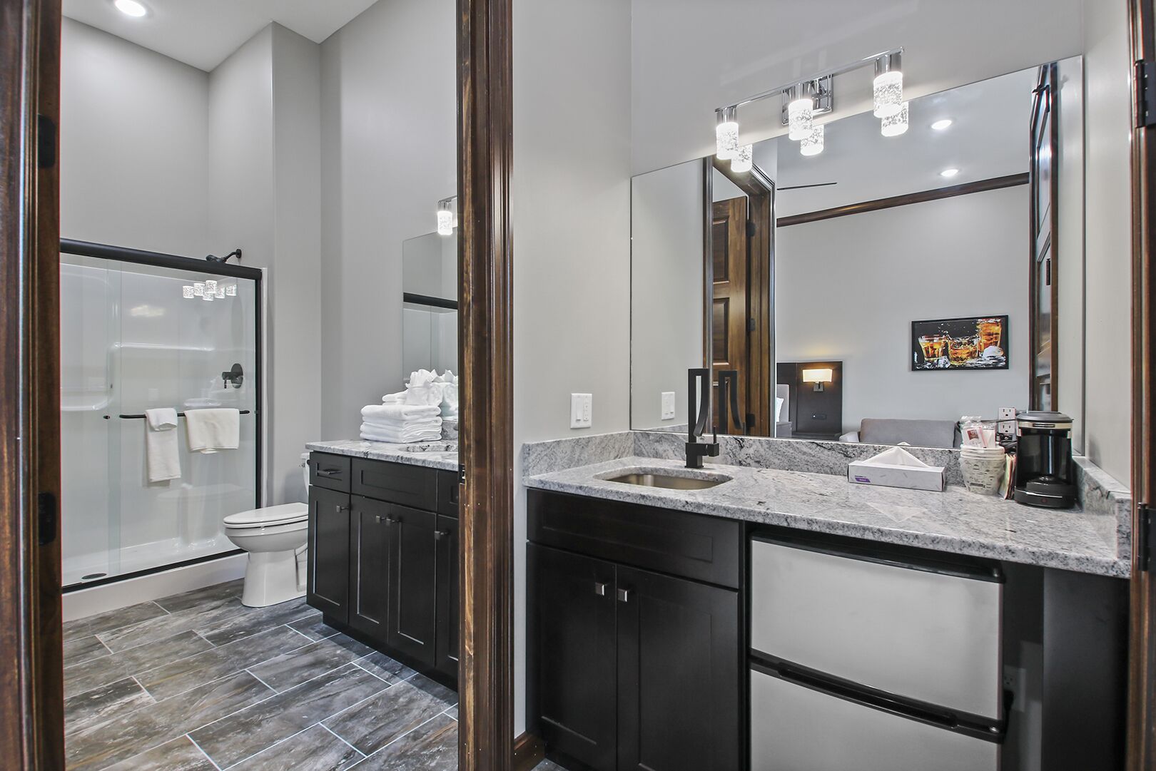 Une salle de bain moderne avec une douche à parois de verre, un grand miroir et un plan de toilette en marbre.