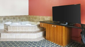 A bathroom with a bathtub, a wooden cabinet, and a television.