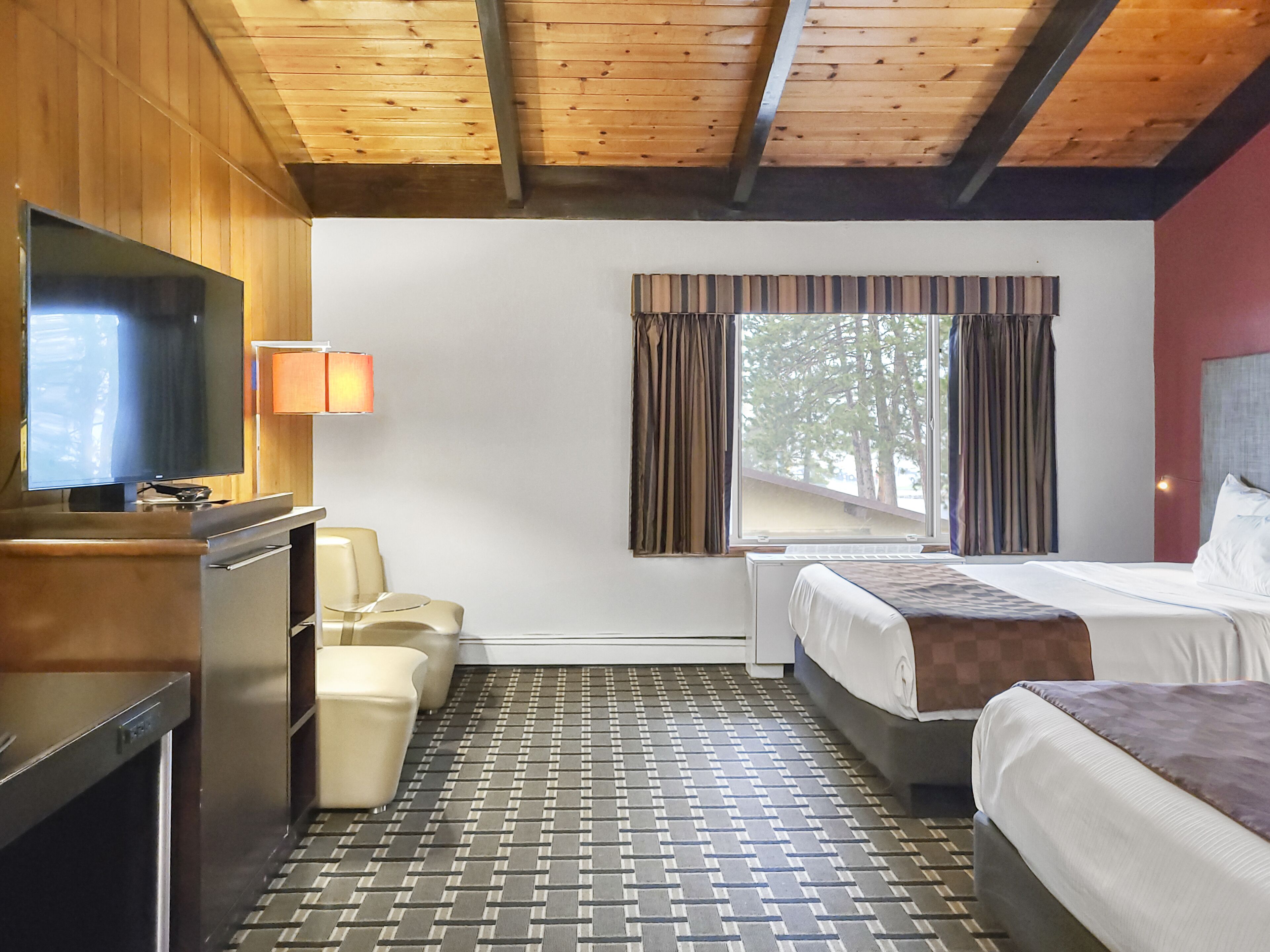 Una habitación de hotel con una cama, televisión, escritorio y una silla.