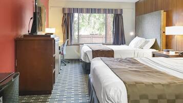 Een hotelkamer met twee bedden, een bureau, een stoel, een televisie en een raam met gordijnen.