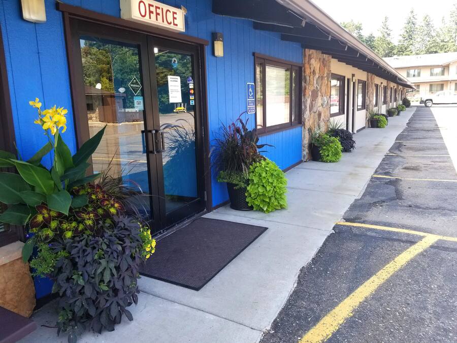 Un motel con fachada azul, un letrero que dice "OFFICE" y un estacionamiento con líneas amarillas.