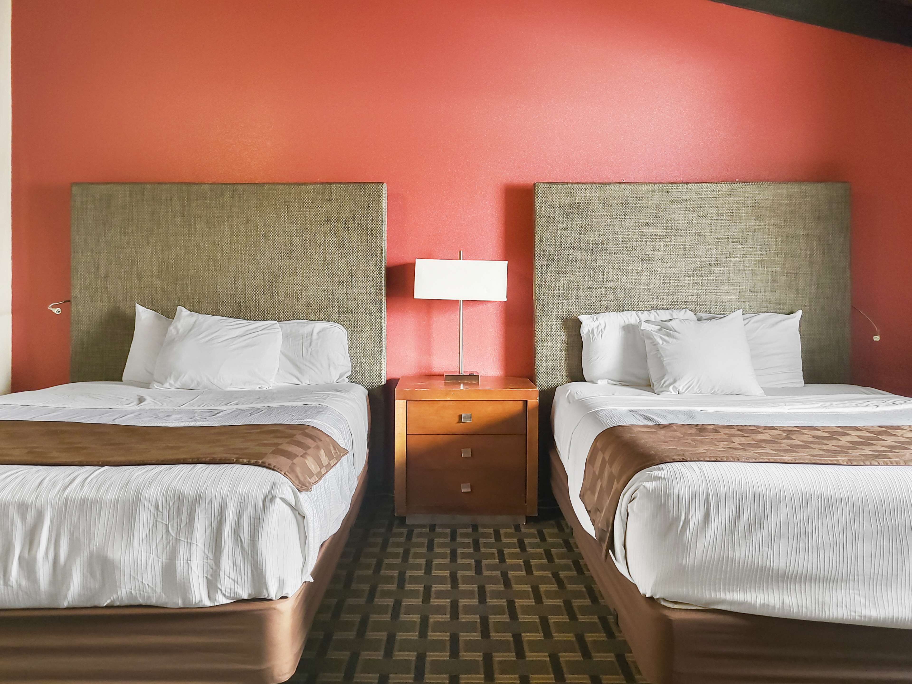 Una habitación de hotel con dos camas, una mesita de noche y una lámpara.