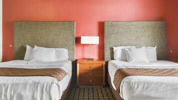 Una habitación de hotel con dos camas, una mesita de noche y una lámpara.