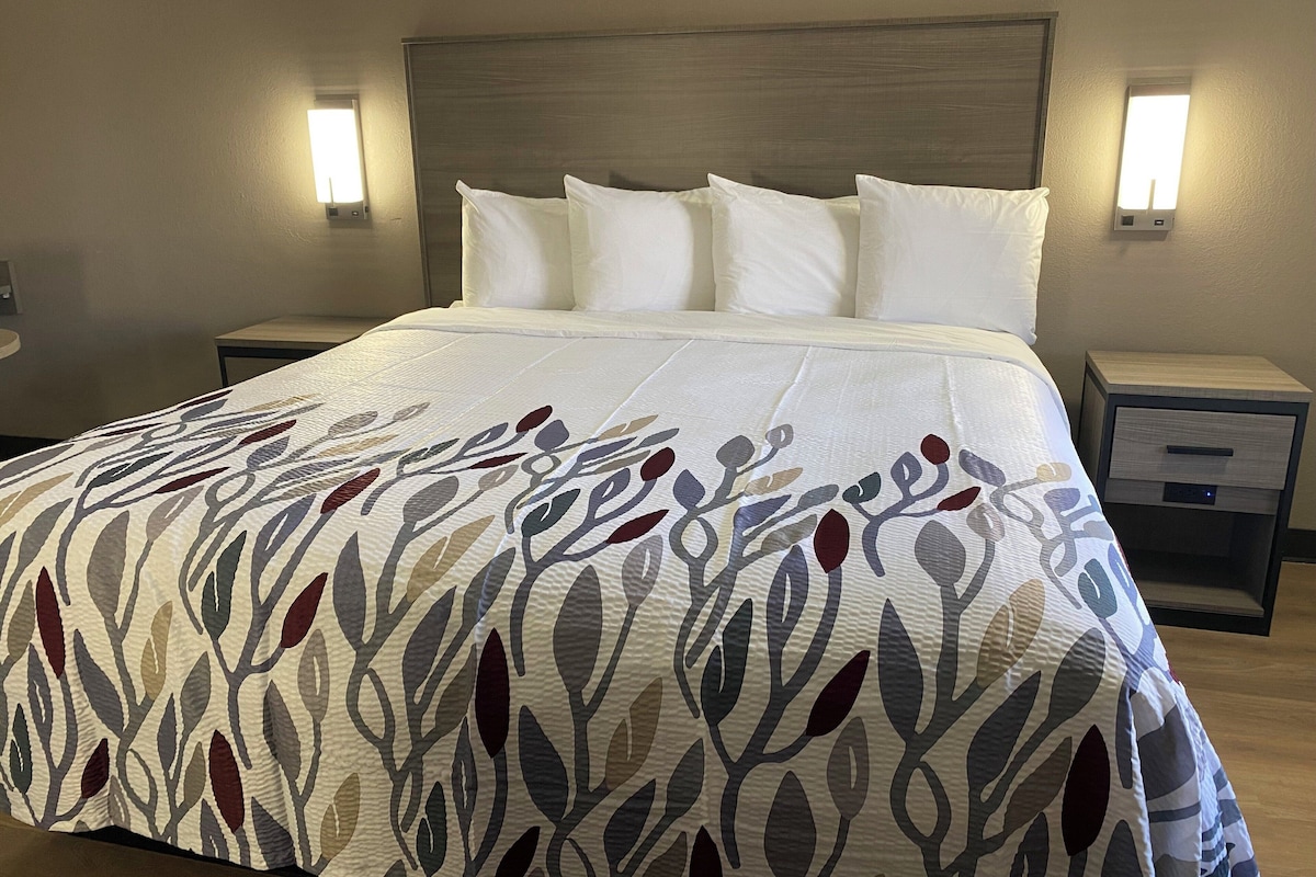 Una cama bien hecha con un edredón estampado, dos mesitas de noche con lámparas y un cabecero.