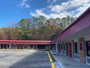 A building with a red roof, a parking lot with marked spaces, and a row of windows on the side. - Red Roof Inn Jacksonville, AL  (Jacksonville)