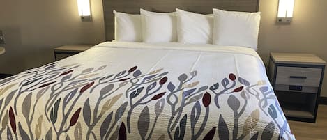 Una cama bien hecha con una colcha estampada, dos mesitas de noche con lámparas y un cabecero de madera.