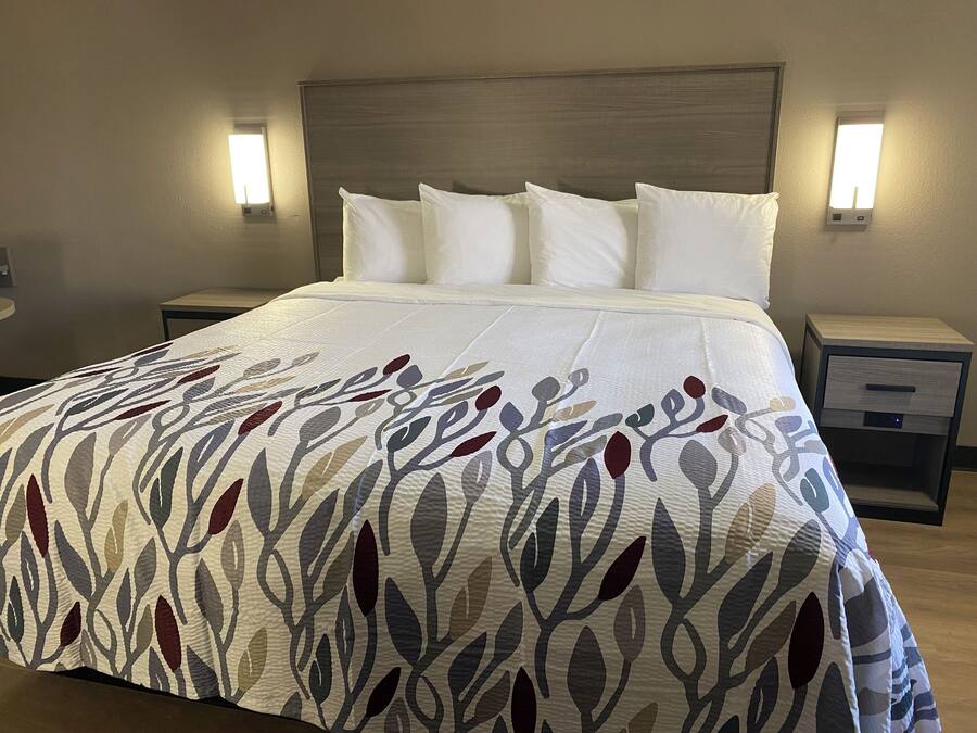 A neatly made bed with a patterned bedspread, two bedside tables with lamps, and a wooden headboard.