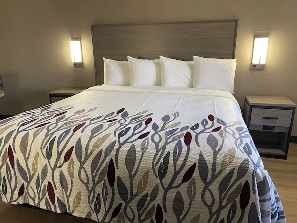 A neatly made bed with a patterned bedspread, two bedside tables with lamps, and a wooden headboard.