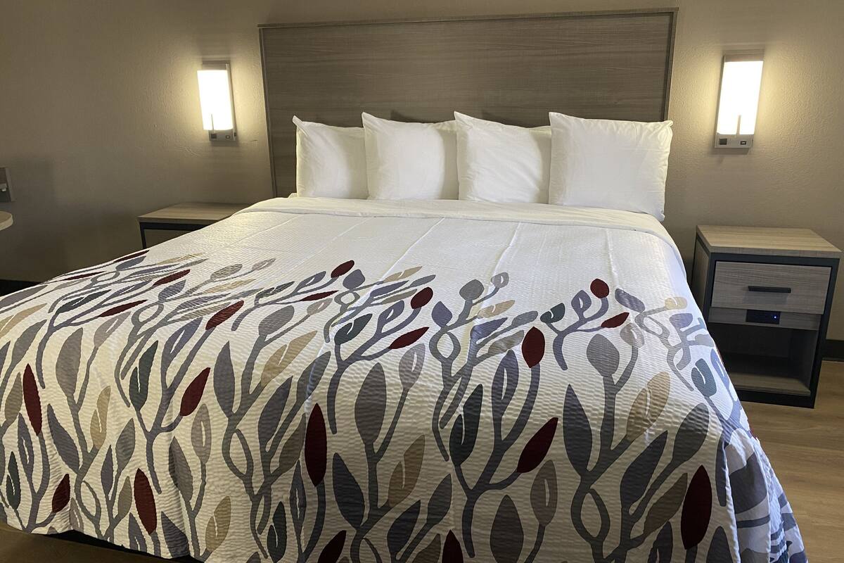 A neatly made bed with a patterned bedspread, two bedside tables with lamps, and a headboard.
