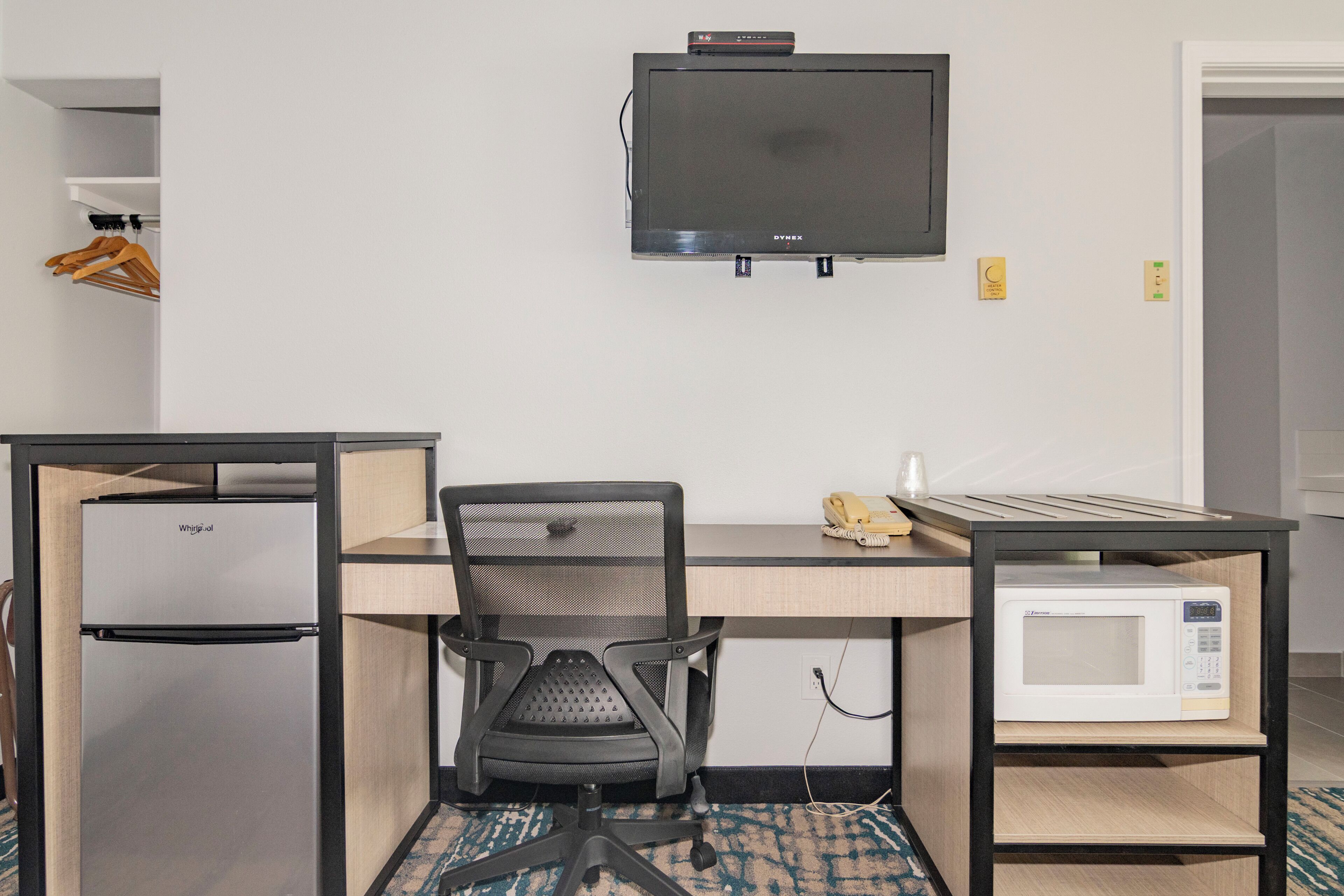 Habitación de hotel con kitchenette, un escritorio y silla, televisor y microondas.