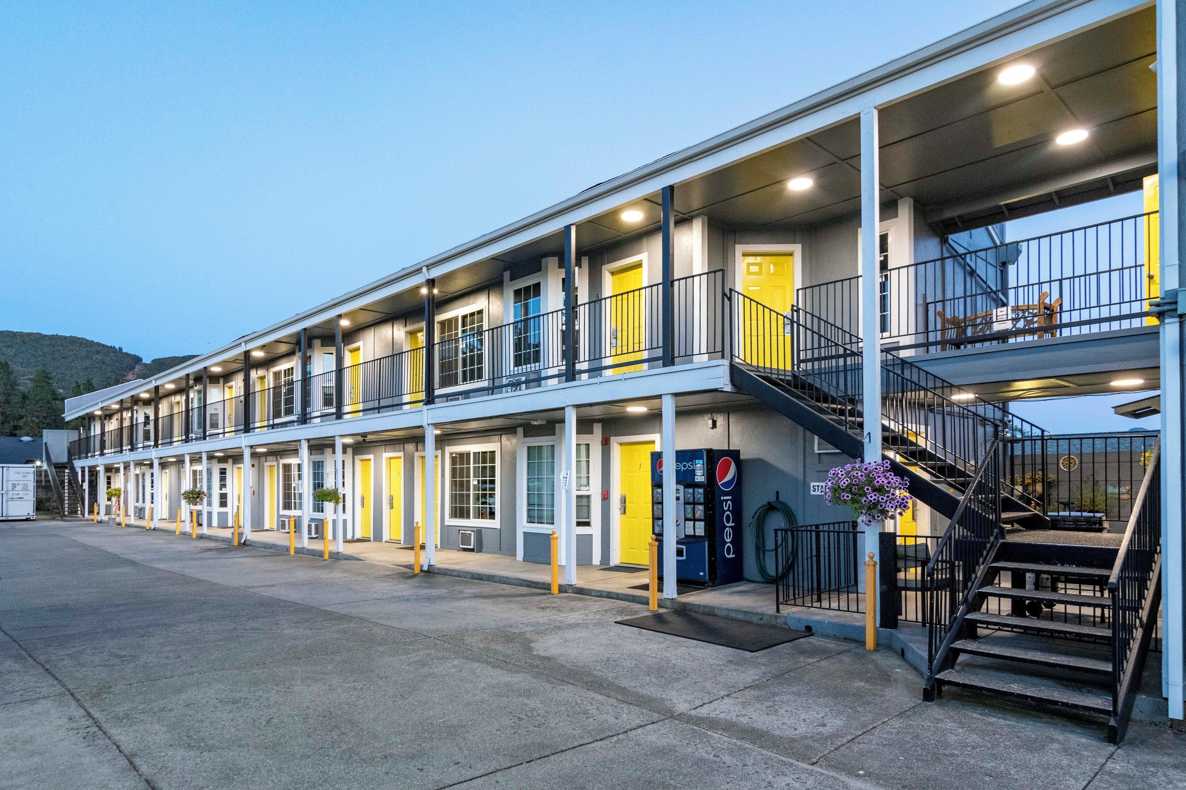 Ein Motel mit mehreren Zimmern, einem Pepsi-Automaten und einer Treppe, die zu einer oberen Etage führt.