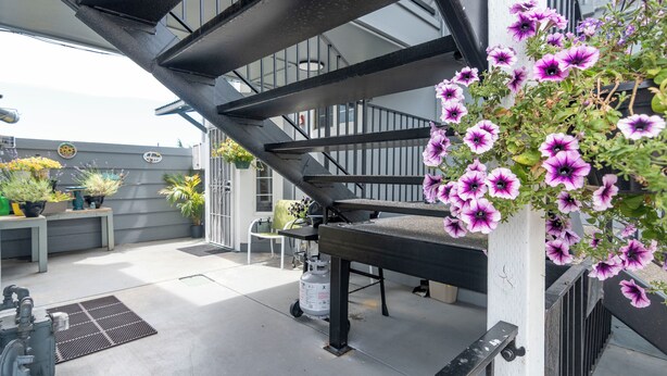 A staircase with a metal railing, a white column, and hanging purple flowers.