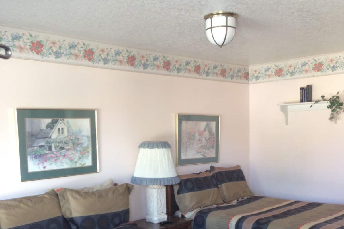 A room with two beds, a lamp, and floral wall decorations.