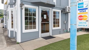 A building with a gray exterior, white trim, and a blue pole with payment logos.