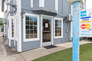 A building with a gray exterior, white trim, and a blue pole with payment logos. - Sweet Breeze Inn (Grants Pass)