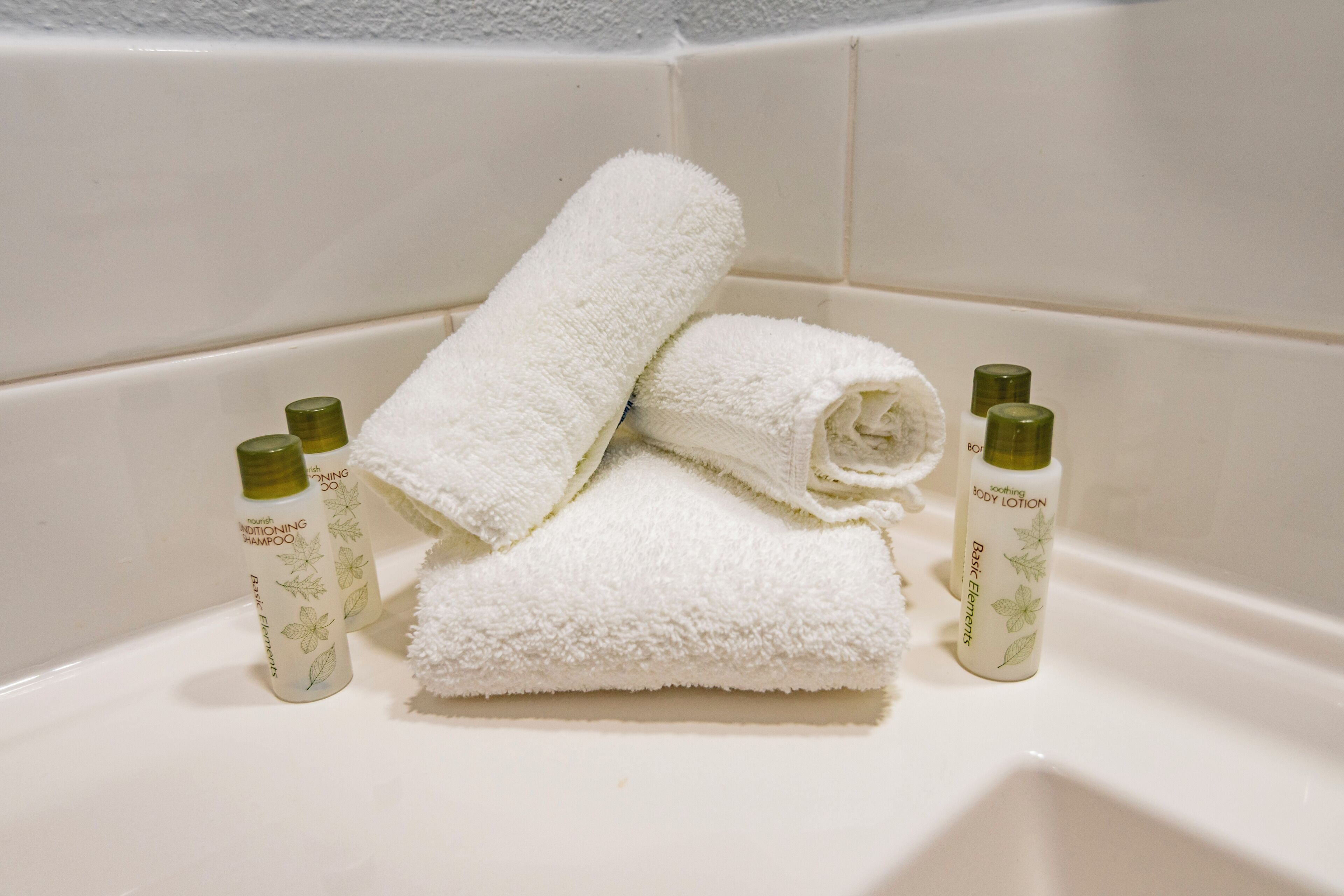 A bathroom with a white bathtub, two bottles of body lotion, and two bottles of shampoo.