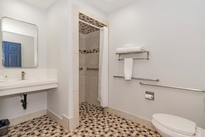 A bathroom with a checkered floor, a white sink, a mirror, a toilet, and a shower area.