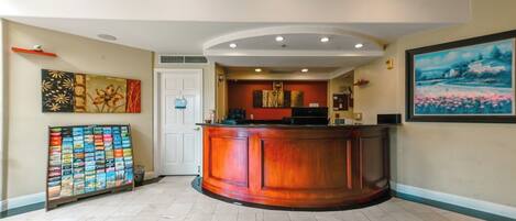 A reception area with a wooden reception desk, a wall-mounted art display, and a tiled floor.