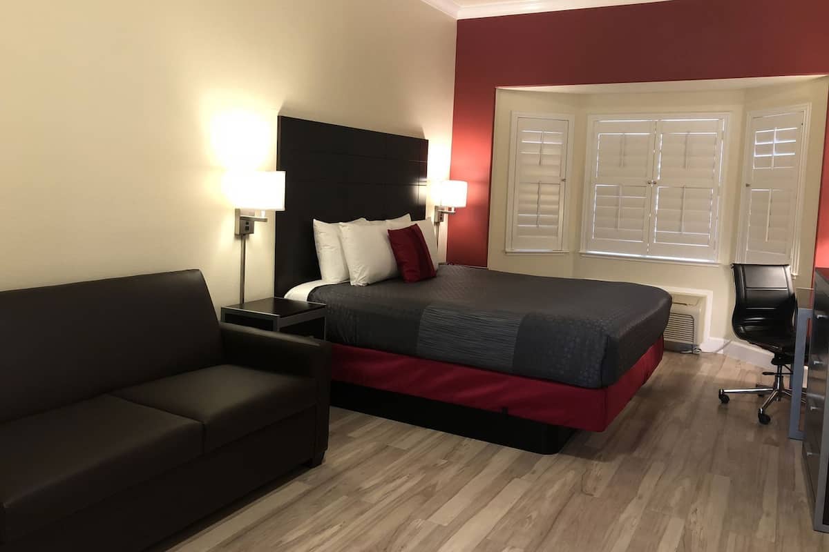 A hotel room with a bed, a sofa, a desk, and a chair.