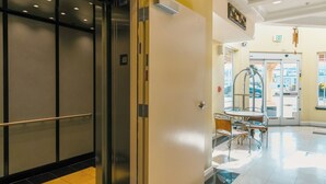 A hotel lobby with a reception desk, a glass door entrance, and a seating area with chairs and a table. - Gateway Inn & Suites San Francisco SFO Airport (San Bruno)