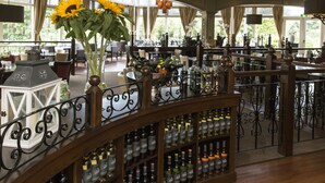 A restaurant with a curved wooden railing, large windows, and a variety of bottles on shelves. - Fletcher Hotel Steenwijk (Steenwijk)