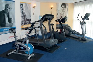 Un gimnasio con cintas de correr, una elíptica y una bicicleta estática.