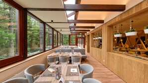 A modern dining area with large windows, wooden beams, and a long table with chairs. - Falkensteiner Club Funimation Katschberg (Rennweg am Katschberg)