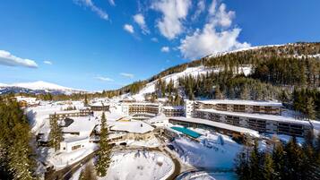 A snow-covered resort with multiple buildings, a pool area, and a ski slope.